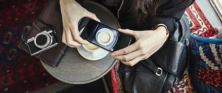 Femme photographiant une tasse de café.